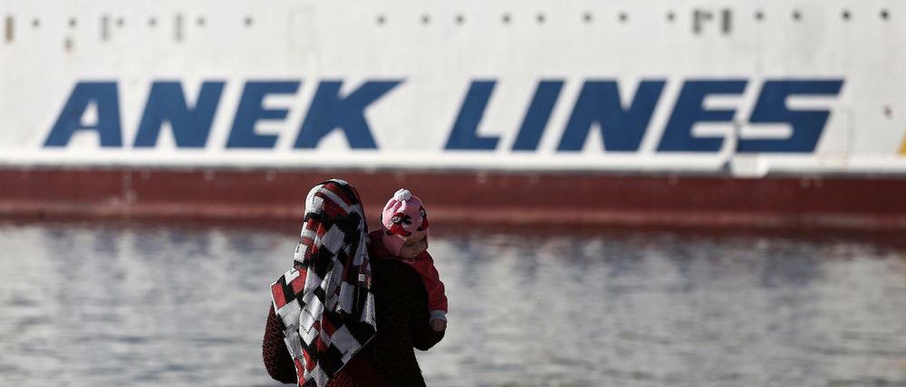 Eine geflüchtete syrische Frau blickt im Hafen von Piräus auf eine Fähre. Der Transport von Flüchtlingen soll nach dem Willen der griechischen Regierung vorerst eingeschränkt werden. 