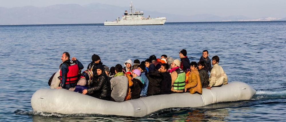 Ein überfülltes Schlauchboot im Mittelmeer. Im Hintergrund ein Schiff der europäischen Grenzschutzagentur Frontex.
