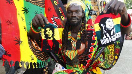 Ein Mitglied der Gruppe Ivoire Binghi bietet Kleidung und Fahnen während des "International Festivals of Abidjan Reggae" zum Verkauf an. 