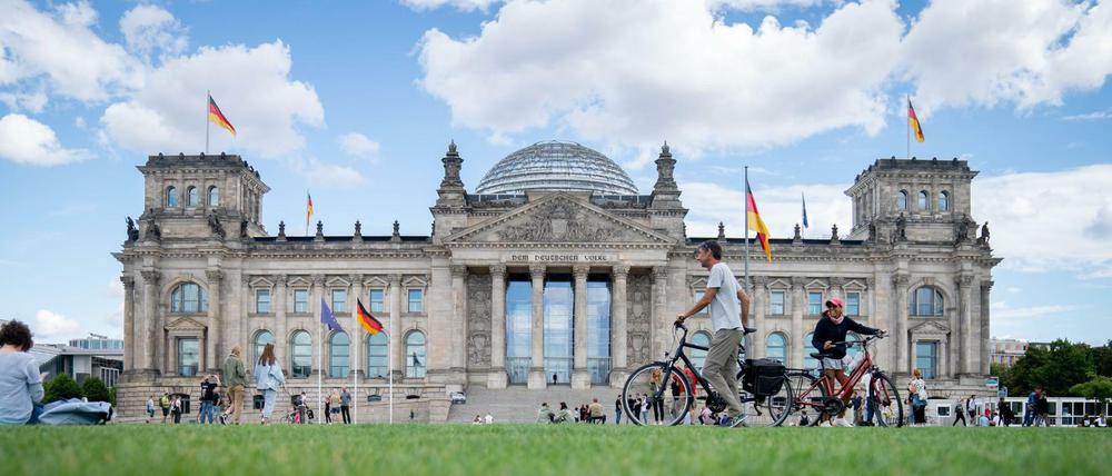 Passanten gehen über die Wiese vor dem Reichstagsgebäude. Seit den Corona-Demonstrationen in Berlin am 29. August wird erneut darüber diskutiert, den Reichstag durch einen Graben zu schützen.
