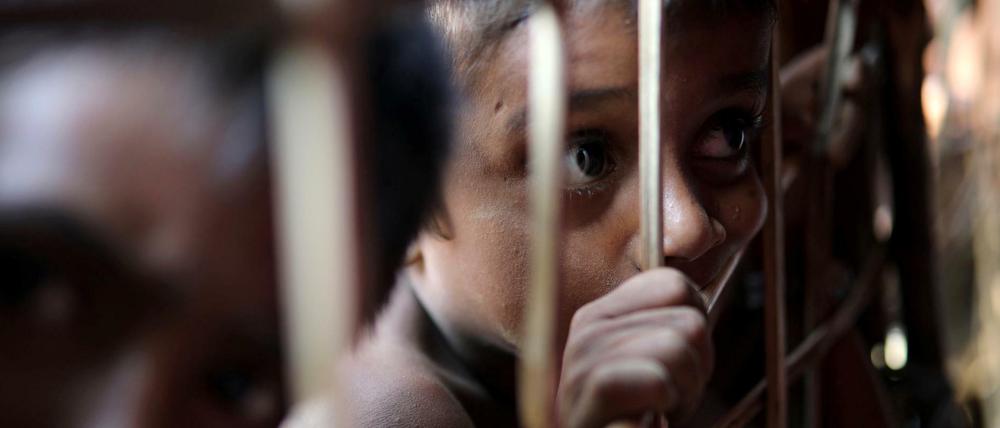 Ein junger Rohingya schaut durch ein Gitter in einem Flüchtlingscamp in Bangladesch.