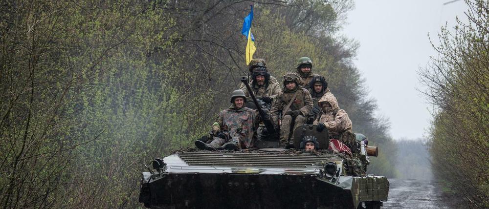 Ukrainische Soldaten fahren auf einem gepanzerten Kampffahrzeug an einem unbekannten Ort in der Ostukraine.