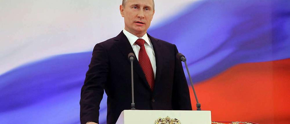 Wladimir Putin legt seine Hand auf die Verfassung.