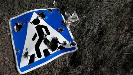 Ein Straßenschild, das durch Streumunition beschädigt wurde, liegt am Stadtrand von Charkiw.