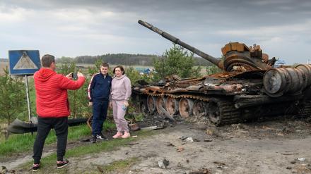 Ein Paar posiert für einen Foto vor einem zerstörten russischen Panzer bei Kiew.