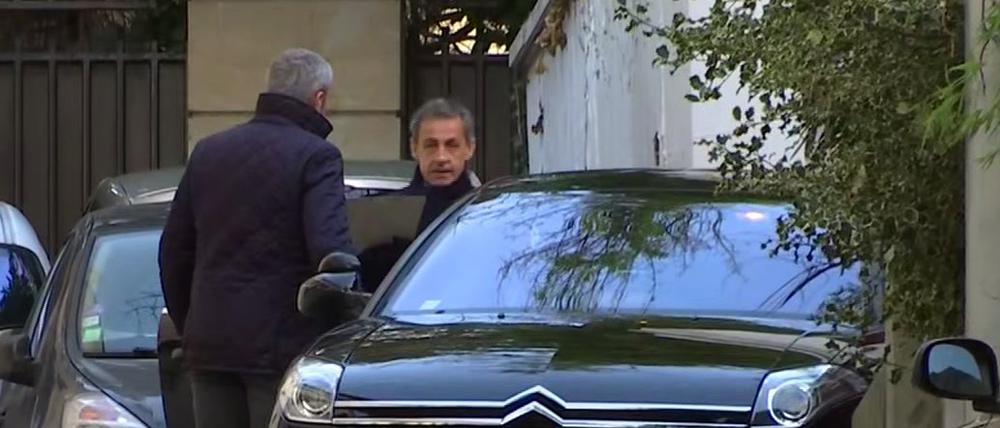 Das Video-Standbild zeigt Nicolas Sarkozy (r), früherer Staatspräsident von Frankreich, als er sein Pariser Zuhause verlässt. 