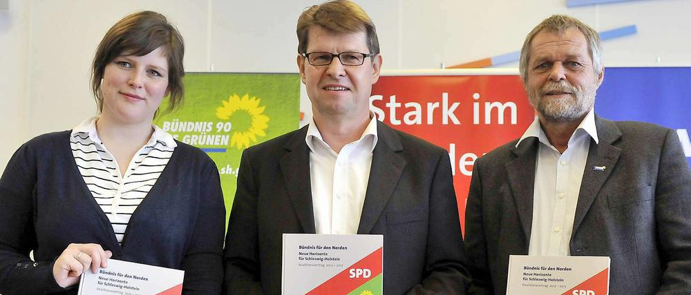 Geschafft: Flemming Meyer vom SSW (rechts), der Landesvorsitzende der SPD, Ralf Stegner, und Grünen-Landesvorsitzende Marlene Loehr halten den Koalitionsvertrag in die Kameras.