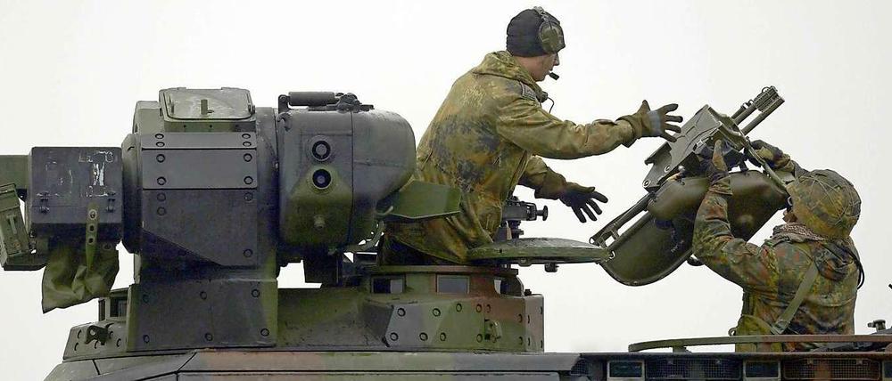 Ein Panzergrenadier reicht dem Kommandant eines Schützenpanzers eine Startvorrichtung für eine Panzerabwehrwaffe vom Typ "Milan".  