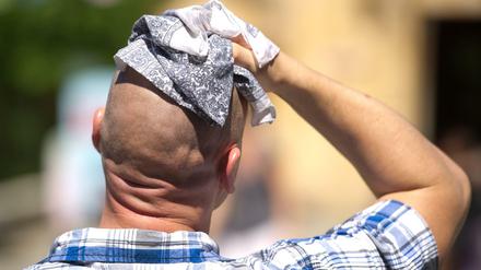 Ein Mann wischt sich in Hannover bei Hitze mit einem Stofftuch über den Kopf.