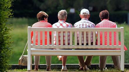 Mehrere ältere Personen sitzen auf einer Parkbank im Schlosspark Pillnitz (Sachsen).