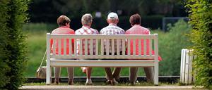 Mehrere ältere Personen sitzen auf einer Parkbank im Schlosspark Pillnitz (Sachsen).