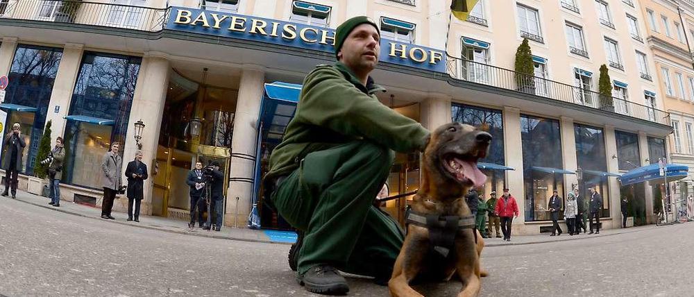 Bitte recht freundlich. Polizist mit Hund vor dem Tagungshotel Bayerischer Hof in München.