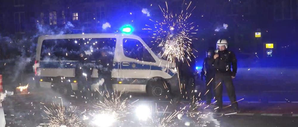 31.12.2022, Berlin: Polizeibeamte stehen hinter explodierendem Feuerwerk. Nach Angriffen auf Einsatzkräfte in der Silvesternacht hat die Diskussion um Konsequenzen begonnen.