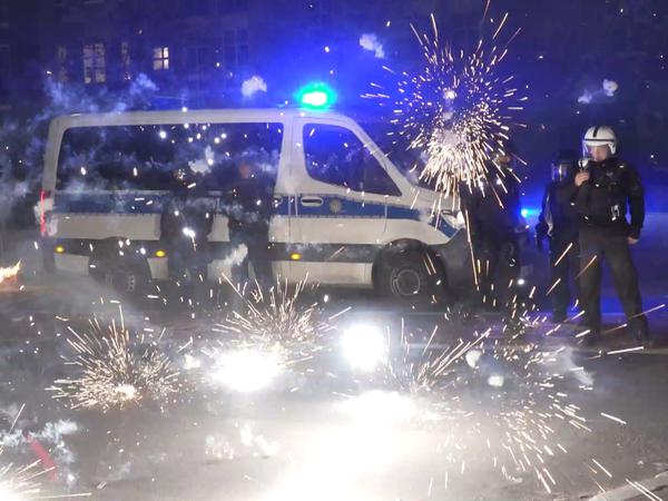 Berliner Polizeibeamte stehen in der Silvesternacht hinter explodierendem Feuerwerk. 