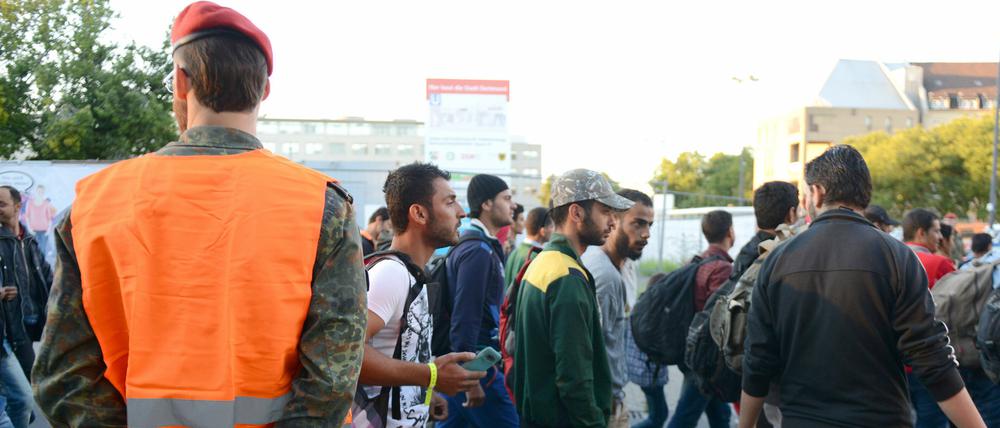 Ein Bundeswehrsoldat steht am Bahnhof in Dortmund nach der Ankunft eines Sonderzuges mit Flüchtlingen und weist den Weg.