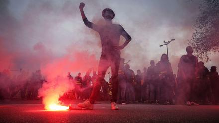 Ein Demonstrant in Lyon steht mit seinem rechten Fuß auf einer Leuchtrakete.