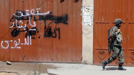 "Bashar, du wirst fallen" steht an der Wand, an der gerade ein Soldat vorbeigeht. Gemeint ist der syrische Machthaber Bashar al Assad. 