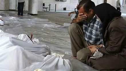 Ein syrische Paar kauert vor verhüllten Leichen. Nach Oppositionsangaben starben die Menschen bei einem Giftgaseinsatz der Armee.