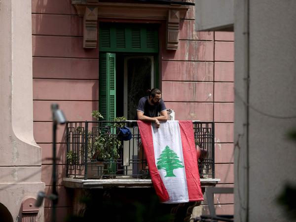 Die Nation als Halt: Im Chaos von Beirut hängt dieser Mann eine Fahne Libanons von seinem Balkon.