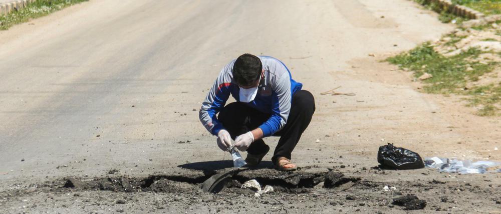 Ein Syrer sammelt nach dem mutmaßlichen Giftgasangriff im syrischen Chan Scheichun Teile von einer Straße ein. 