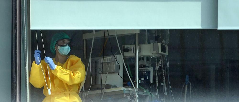 Ein Mitarbeiter in Schutzkleidung steht am Fenster des Krankenhauses La Paz in Madrid.
