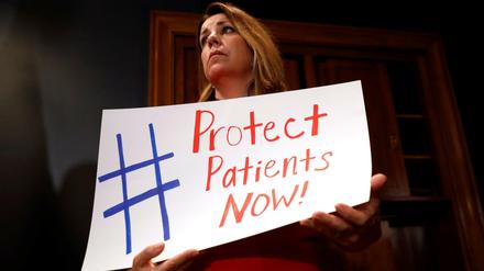 Eine Frau demonstriert mit einem Schild für den Erhalt der Krankenversicherung am Rande der Kongress-Beratungen.