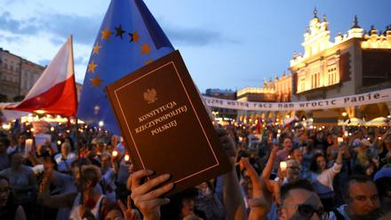 Demonstranten im polnischen Krakau halten die Verfassung des Landes hoch - und eine Fahne der EU. 