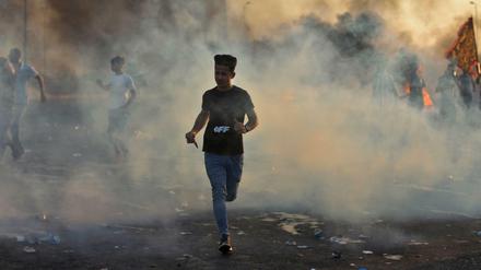 Junge Demonstranten rennen durch den Rauch, der aus brennenden Reifen auf den Straßen Bagdads aufsteigt.