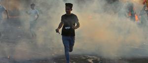 Junge Demonstranten rennen durch den Rauch, der aus brennenden Reifen auf den Straßen Bagdads aufsteigt.