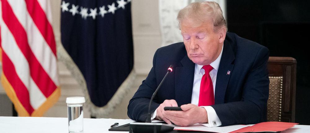 Der damalige US-Präsident Donald Trump benutzt sein Smartphone.