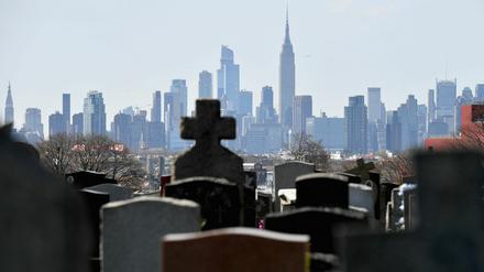 Grabsteine auf dem Linden Hill Methodist Cemetery mit der Skyline von Manhattan im Hintergrund.