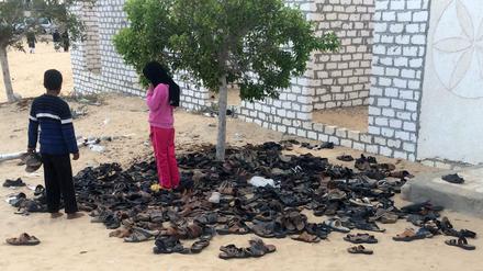 Kinder betrachten vor der Moschee in Bir al-Abd (Ägypten) die Schuhe von Opfern des Terroranschlags.