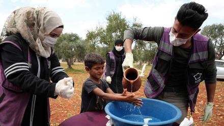 Freiwillige Helfer bringen einem syrischen Flüchtlingskind richtiges Händewaschen bei.