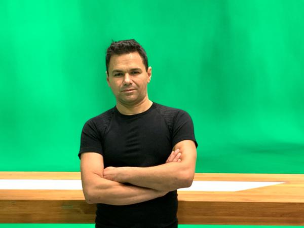 Özden Terli im Studio, in der Sendung ist der grüne Hintergrund animiert mit den Wettergrafiken und Karten.