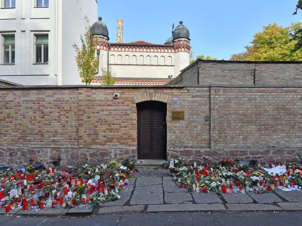 Blumen und Kerzen stehen neben der Tür zur Synagoge in Halle. Hier wurden im Oktober 2019 zwei Menschen erschossen.