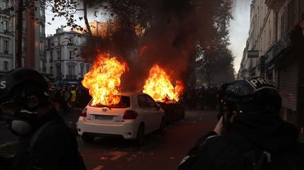 Zwei Autos brennen in Paris während der Demonstration gegen das umstrittene Sicherheitsgesetz.