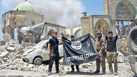 Männer der irakischen Anti-Terroreinheit halten eine umgedrehte IS-Fahne hoch. 