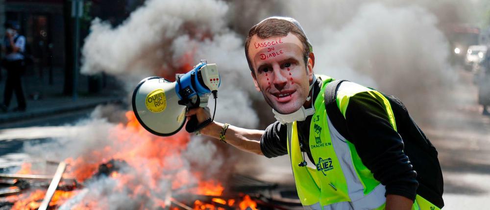 Ein Demonstrant in Paris mit einer Maske von Präsident Macron 
