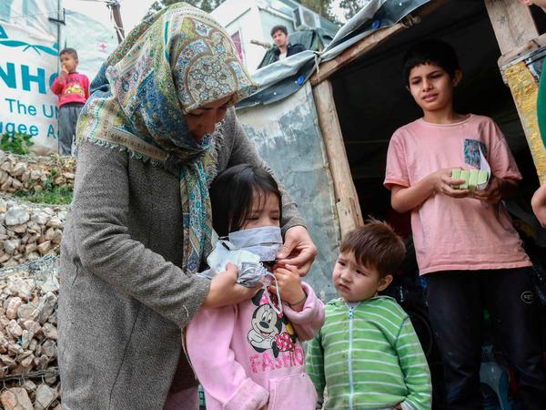 Camp Moria auf Lesbos: Eine Frau legt Kindern handgefertigte Schutzmasken an. 