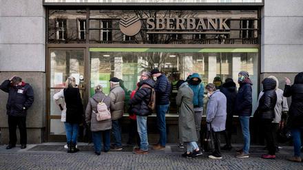 Bankkunden stehen vor einer Sberbank-Filiale in Prag Schlange. 