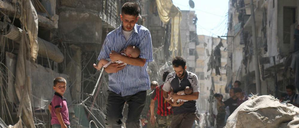 Die syrische Zivilbevölkerung leidet am meisten unter den beständigen Angriffen. Hier versuchen Männer in der von Ruinen geprägten nördlichen City von Aleppo, Babys vor den Luftangriffen in Sicherheit zu bringen. 