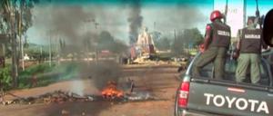 Polizisten passieren einen Brandherd auf einer Straße in Jos in Nigeria.