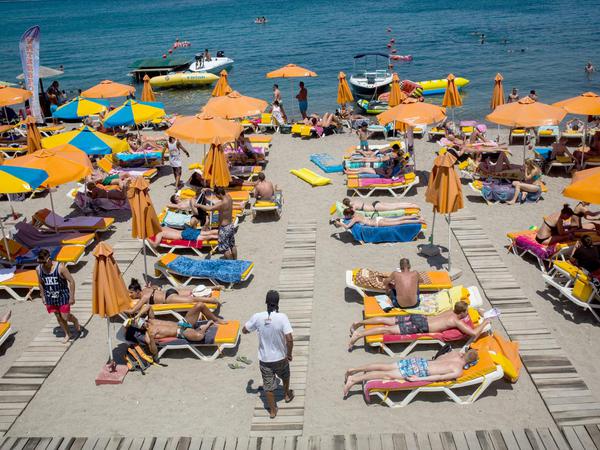 Touristen an einem Strand nahe der Stadt Kos auf der gleichnamigen griechischen Insel