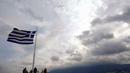 Alle Augen richten sich auf Athen. Touristen stehen auf der Akropolis unter der griechischen Nationalflagge.