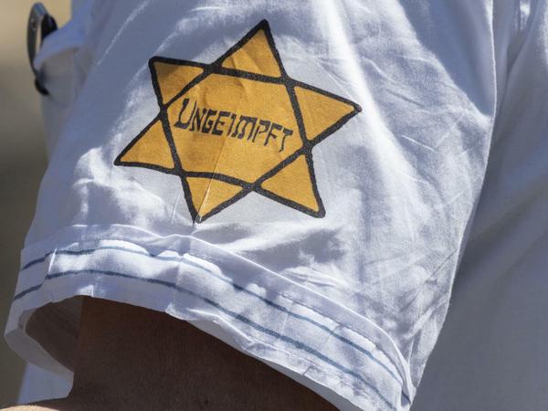 Auf einer Demonstration in Frankfurt/Main trägt ein Mann ein T-Shirt mit einem gelben Stern und der Aufschrift "Ungeimpft". 