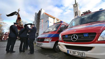 Angehörige der Feuerwehr stehen vor Beginn der Trauerfeier für einen getöteten Feuerwehrmann vor der Pfarrkirche St. Ägidius in Neusäß.