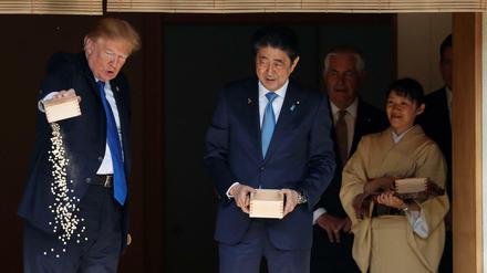 Eat this: US-Präsident Donald Trump schüttet Fischfutter über Koi-Karpfen aus - zuvor hatte es ihm Japans Premierminister vorgemacht. 