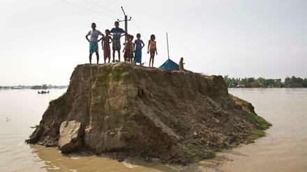 Dorfbewohner warteten im vergangenen August auf einer von den Überschwemmungen zerstörten Straße in Guwahati (Indien) auf Hilfsgüter. 