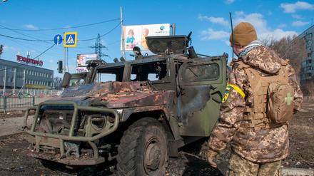 Ein ukrainischer Soldat inspiziert ein beschädigtes Militärfahrzeug in Charkiw.