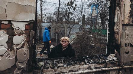 Eine Frau an einem durch Bomben zerstörten Haus in Irpin
